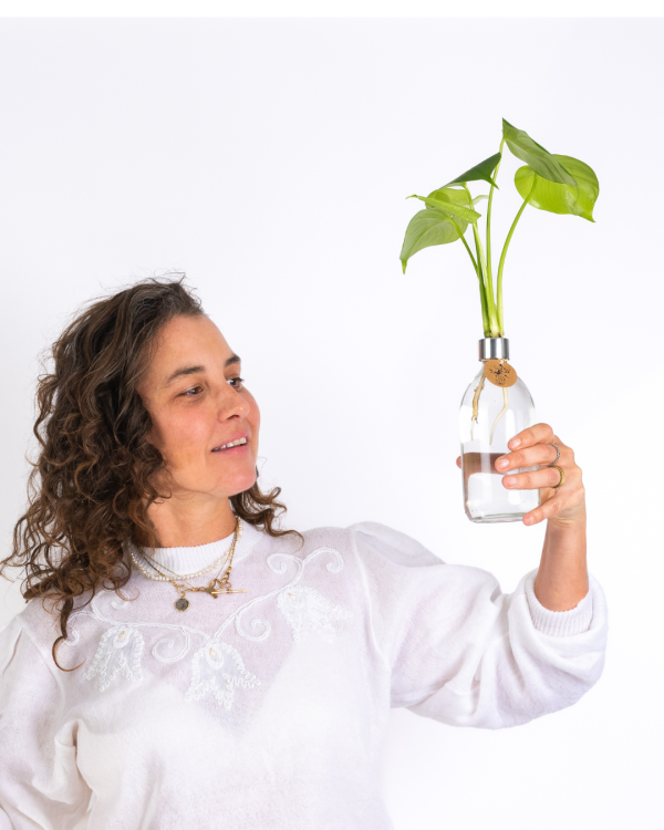 אישה מחזיקה בקבוק עם צמח הידרופוני